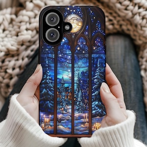 Może przedstawiać: Czarne etui na telefon z witrażem przedstawiającym zimową scenerię. Grafika przedstawia pełnię księżyca, gwiazdy, ośnieżone drzewa i zapalone świece. Etui ma czarną obwódkę i dwa obiektywy aparatu.