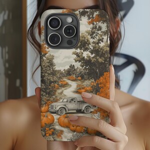May include: A phone case featuring a fall scene with a winding road, pumpkins, and a vintage pickup truck. The case has a beige background with orange and green trees. The phone case is designed to fit a smartphone.