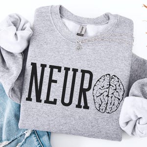 Puede incluir: Sudadera gris con la palabra "NEURO" impresa en negro y un gráfico de cerebro en blanco y negro.
