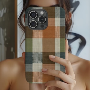 May include: A smartphone case featuring a woven-look plaid pattern in shades of burnt orange, sage green, dark charcoal, and cream. The case has a rectangular shape with rounded corners and a cutout for the rear camera lens array.