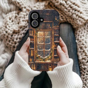May include: A phone case featuring a cozy winter scene. The design depicts a window with a snowy view, surrounded by bookshelves and a festive garland. The case has a dark background with falling snow and a camera cutout.