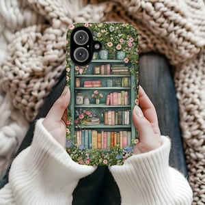 Könnte beinhalten: Eine Handyhülle mit einer detaillierten Illustration eines Bücherregals voller Bücher, Blumen und Pflanzen. Die Hülle hat einen tealfarbenen Hintergrund und ist von floralen Ranken umgeben. Das Design ist eine skurrile und künstlerische Darstellung einer gemütlichen Leseecke.