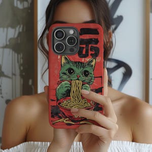 Puede incluir: Funda de teléfono roja con un gato verde comiendo fideos ramen. El diseño incluye texto japonés y un cuenco rojo con fideos. El gato tiene ojos grandes y palillos. La funda está diseñada para un teléfono inteligente.
