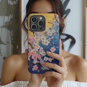 May include: A phone case with a floral design featuring pink, white, and blue flowers on a blue and yellow background. The case has a camera lens cutout.