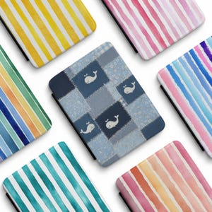 May include: A collection of colorful tablet cases with various designs. One case features a patchwork pattern with whale illustrations. Other cases display watercolor stripes in shades of yellow, pink, blue, green, and orange.