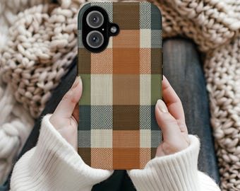 May include: A smartphone case featuring a plaid pattern in shades of brown, orange, green, and cream. The case has a dual-lens camera cutout and is held by a person wearing a white sweater.