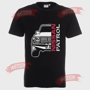 May include: Black t-shirt with a white outline of a Nissan Patrol 4x4. The text "NISSAN PATROL" is printed vertically in red and white. The shirt has a crew neck and is made of a soft material.