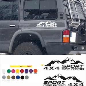 Può includere: Adesivo nero e bianco con il testo "4x4 Sport Off Road" e una grafica di una catena montuosa. L'adesivo è mostrato sul retro di un SUV grigio.