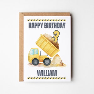 May include: A white birthday greeting card featuring a yellow dump truck illustration, a pile of dirt, a traffic cone, and the text HAPPY BIRTHDAY and WILLIAM. The design includes yellow and black caution stripes at the top and bottom edges.