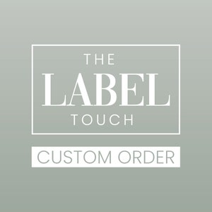 May include: A square graphic design on a sage green background featuring the white text THE LABEL TOUCH enclosed in a thin white rectangular border, with the white text CUSTOM ORDER positioned below the border in a separate white rectangle.