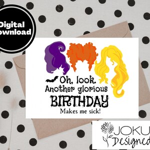 May include: A white card with a black bat, three witches with purple, orange, and yellow hair, and the text "Oh, look. Another glorious BIRTHDAY Makes me sick!"  The card has a brown envelope behind it and a white background with black polka dots.