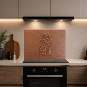May include: A rectangular copper-colored kitchen backsplash panel featuring a detailed, embossed silhouette of a human head and torso formed by intricate, branching tree-like root patterns, centered behind a black stovetop and oven range.