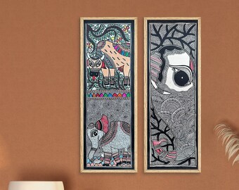Può includere: Un mobile in legno marrone chiaro con una parte anteriore in rattan intrecciato e due ripiani aperti. Il mobile è decorato con due illustrazioni in bianco e nero incorniciate di animali e piante. Il mobile è davanti a una parete in terracotta con una porta che conduce a una sala da pranzo.