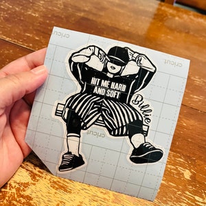 Pode incluir: Adesivo preto e branco de uma pessoa usando um boné de beisebol e uma camisa listrada com o texto "Hit me hard and soft" e "Billie" nele.