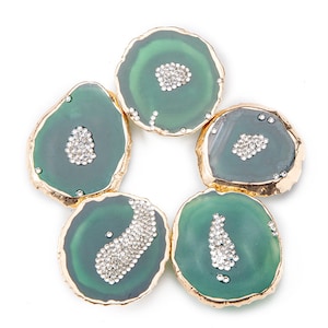 Könnte beinhalten: Fünf grüne Achat-Untersetzer mit goldener Einfassung und einem Strassstein-Cluster in der Mitte jedes Untersetzers.