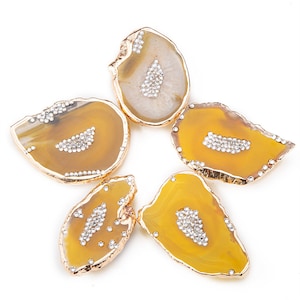 May include: Five yellow agate slices with gold trim and clear rhinestones. The agate slices are irregular in shape and have a natural, organic look.