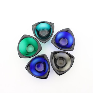 May include: Five small, triangular glass bowls arranged in a circular pattern. Each bowl features a dark, opaque outer rim and a vibrant, translucent interior basin in shades of teal, bright blue, deep green, dark blue, and charcoal gray.