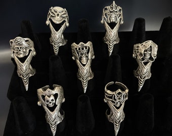 May include: Eight silver skull rings with intricate designs. Each ring features a different skull design with detailed carvings and a pointed, claw-like extension.