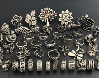 May include: A collection of 35 silver toe rings with various designs, including a tree, a sunflower, a butterfly, a leaf, a heart, a snake, and a dragon.