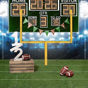 May include: A football-themed backdrop featuring a green scoreboard with the text HALF TIME, HOME, VISITOR, QTR, DOWN, and TO GO. A yellow goalpost stands on a green field with a wooden crate, a white 1/2 sign, and three brown footballs.
