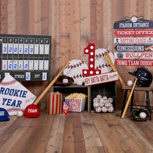 May include: A baseball-themed display with a scoreboard, baseballs, bats, and signs. Includes a red number 1, a baseball helmet, and a banner that says "Rookie Year". The scene is set on a wooden background.