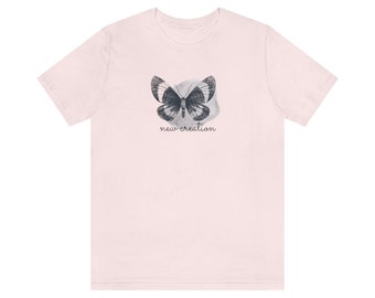 May include: A pink t-shirt with a black and white butterfly graphic and the text "new creation" printed on the front.