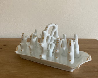 May include: White porcelain bread knife holder with a gold trim. The holder is shaped like a series of branches with gold dots.