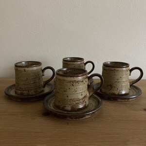 May include: Set of four brown and beige speckled ceramic coffee mugs with matching saucers.
