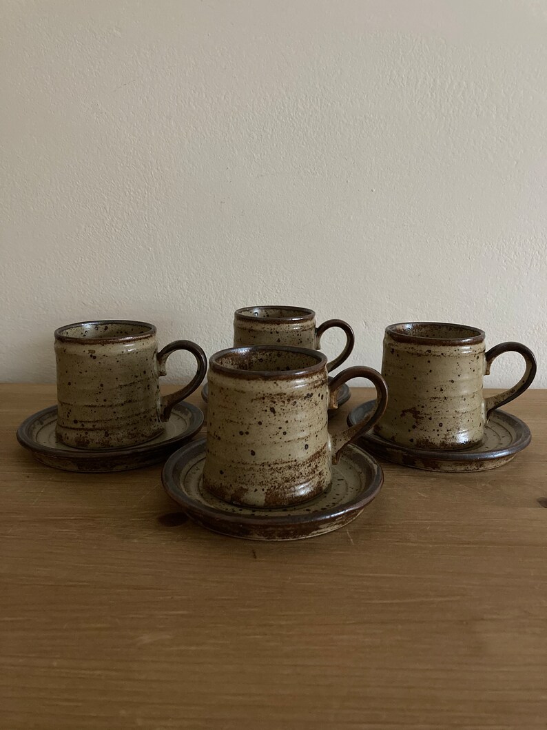May include: Set of four brown and beige speckled ceramic coffee mugs with matching saucers.