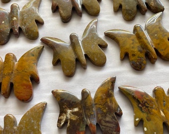 May include: A collection of polished stone butterfly carvings in shades of brown, red, and yellow. The butterflies are all different sizes and shapes, but they all have a similar design.
