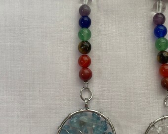 May include: Two silver keychains with a circle of aquamarine stones in the shape of a tree. Each keychain has a silver ring and a string of seven colorful beads.