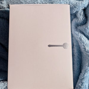 May include: A white box with a silver keyhole design on the front.
