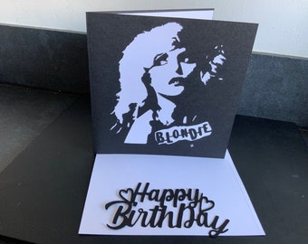 May include: A black and white card with a silhouette of a woman with the word "Blondie" printed on it. The card is open to reveal a white card with the words "Happy Birthday" printed in black.
