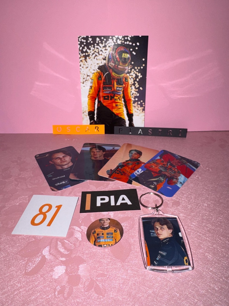 Puede incluir: Una colecci&oacute;n de merchandising de fans con un piloto de F&oacute;rmula 1. Incluye una foto grande, cromos, un llavero, un bot&oacute;n y un letrero con el n&uacute;mero 81. Los art&iacute;culos son de color naranja, negro y blanco.