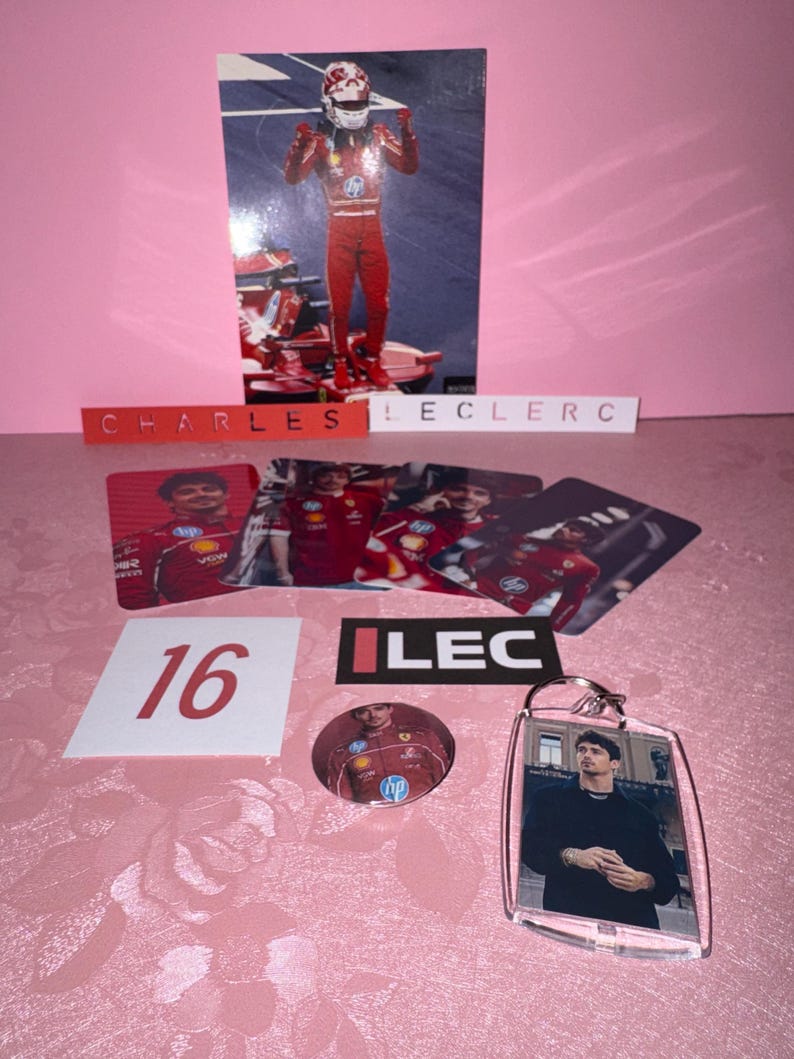 Puede incluir: Una colecci&oacute;n de recuerdos de Charles Leclerc, que incluye una foto suya con un traje de carreras rojo, un llavero, una chapa y varias tarjetas. El n&uacute;mero 16 se muestra en un cuadrado blanco, y el nombre "CHARLES LECLERC" est&aacute; escrito.