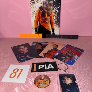 Puede incluir: Colecci&oacute;n de merchandising para fans de F&oacute;rmula 1, con un piloto. Incluye un p&oacute;ster grande, cromos, un llavero, una chapa y una pegatina con el n&uacute;mero 81. Los colores son naranja, negro y blanco.