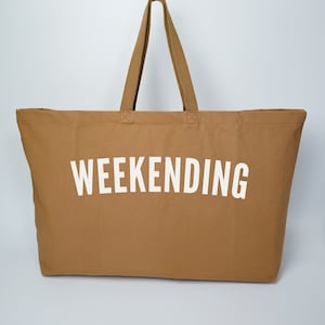 May include: A brown canvas tote bag with white handles and the word "WEEKENDING" printed in white on the front.