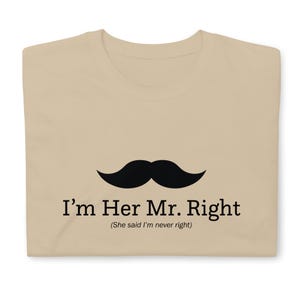 May include: A beige t-shirt with a black mustache graphic and the text "I'm Her Mr. Right (She said I'm never right)"