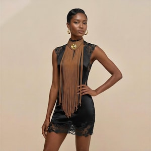 May include: A black satin mini dress with lace trim. The dress is paired with a statement necklace featuring a gold pendant and long, brown fringe. Gold hoop earrings complete the look. The outfit is elegant and stylish.