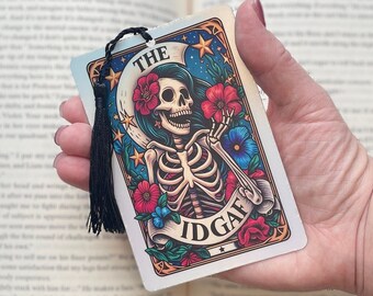 May include: A colourful bookmark featuring a skeleton with floral accents and the text "The Idgaf".