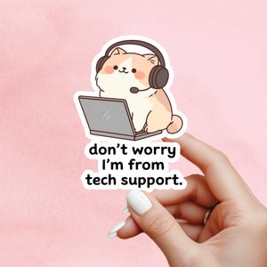 May include: A sticker showing a cartoon cat with a headset and laptop. The cat is beige and white with pink cheeks. The text on the sticker says "don't worry I'm from tech support."