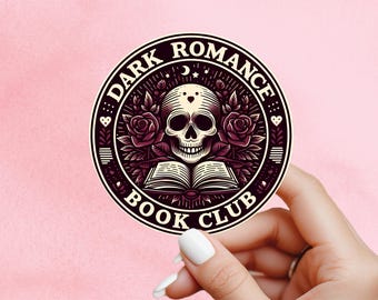 May include: A circular sticker with the words "DARK ROMANCE BOOK CLUB" around a central image. The image shows a skull, an open book, roses, and stars in burgundy and cream colours.