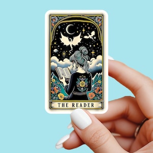 May include: A sticker depicting a woman reading a book, set against a night sky with dragons and floral details. The text "THE READER" is at the base. The woman wears a black dress with floral embroidery. The sticker has a decorative border.