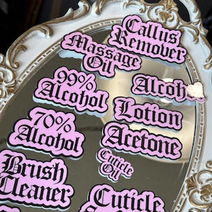 May include: Pink and black stickers with various nail care product labels, including "Callus Remover", "Massage Oil", "99% Alcohol", "70% Alcohol", "Alcohol Lotion", "Acetone", "Cuticle Oil", "Cuticle Softener", "Brush Cleaner", and "Clear Acrylic".
