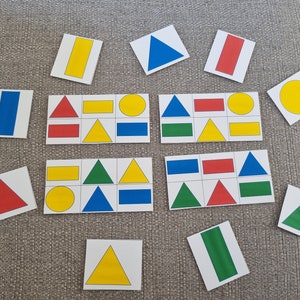 Peut inclure: Un ensemble de cartes de formes colorées avec des formes rouges, bleues, jaunes et vertes. Les cartes sont disposées en grille sur une surface texturée grise.