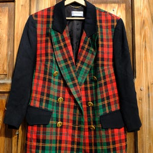May include: A red, green and black plaid blazer with a double-breasted closure and gold buttons. The blazer has black sleeves and a black collar.