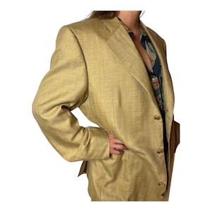 Peut inclure: Un blazer beige avec une fermeture simple boutonnage et trois boutons. Le blazer a un tissu texturé et une coupe légèrement ample.