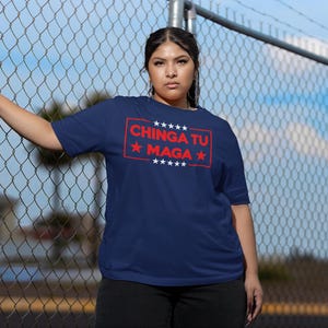 May include: Navy blue t-shirt with the text "CHINGA TU MAGA" in red, framed by a red rectangle and stars. The shirt is short-sleeved and has a crew neck.