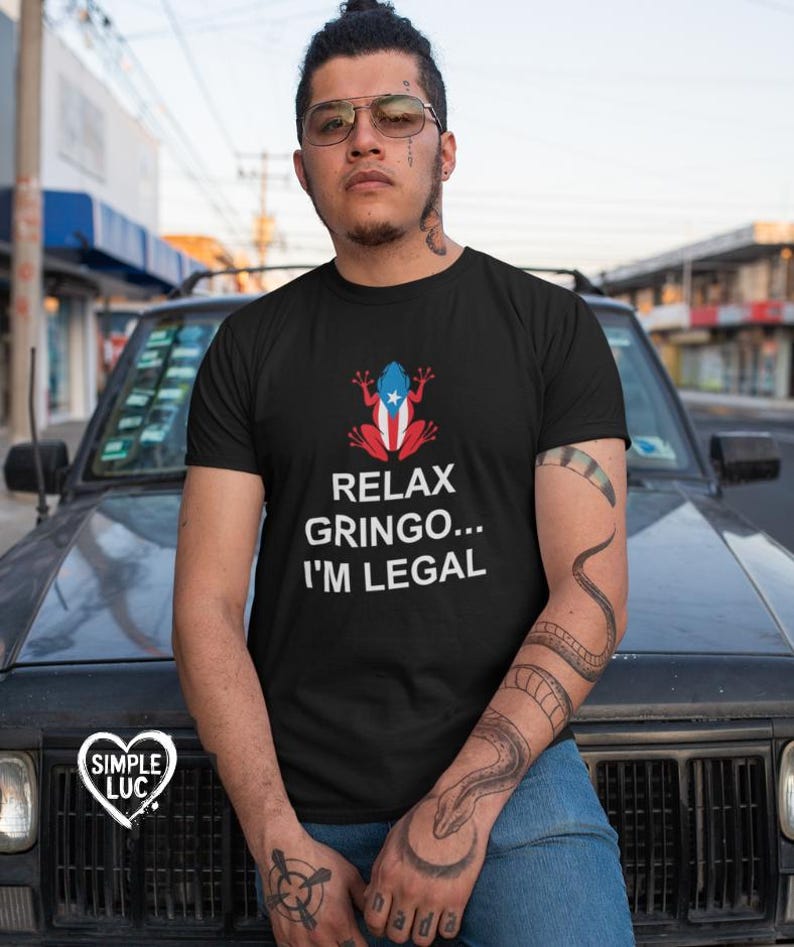May include: Black t-shirt with a white frog wearing a Puerto Rican flag. The text "Relax Gringo... I'm Legal" is printed on the shirt.