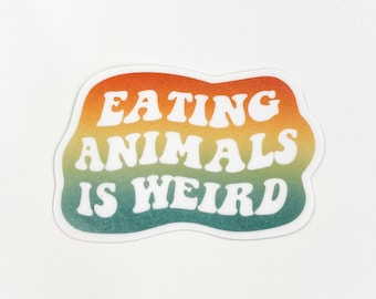 May include: A sticker with a gradient background of orange, yellow, and green. The white text reads "EATING ANIMALS IS WEIRD" in a retro font. The sticker has a wavy, irregular shape and is set against a white background.